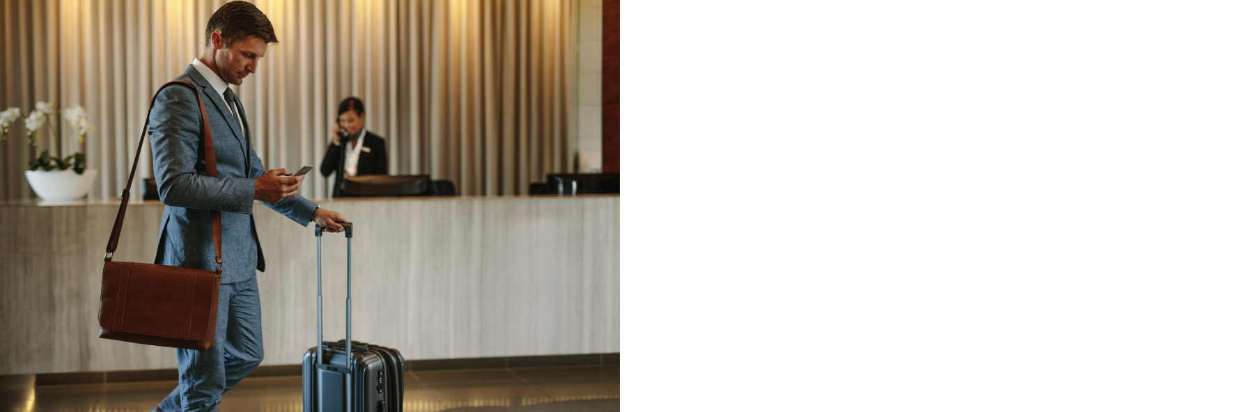Geschäftsreisender mit Rollkoffer in einer hellen Hotellobby